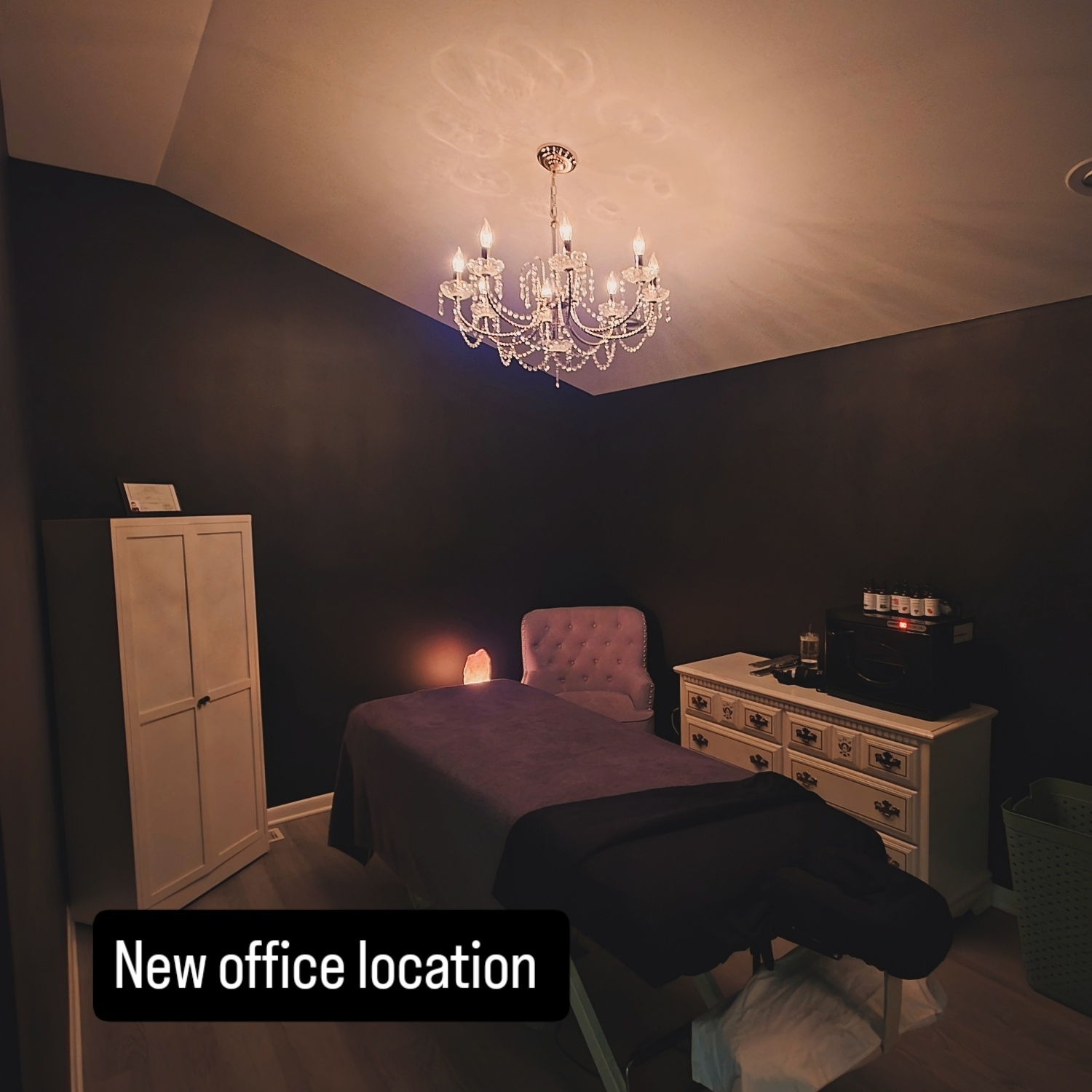 Treatment room with chandelier, massage table and salt lamp